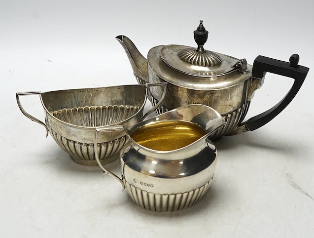 A matched late 19th/early 20th century demi-fluted silver three piece tea set, London, 1884 and later, gross weight 15.5oz. Condition - poor to fair